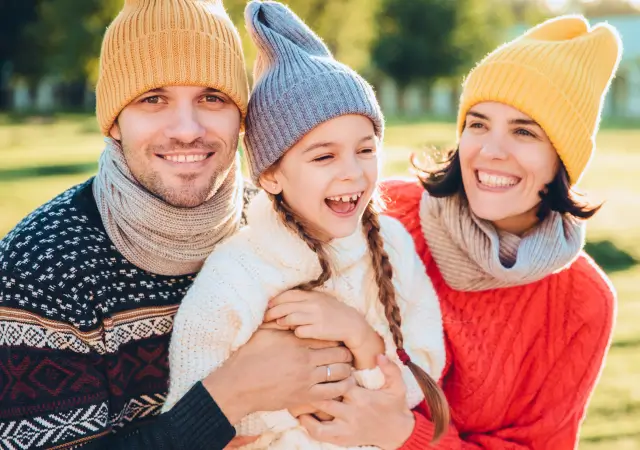 Padres e hija usando ropa abrigada por la temporada de invierno