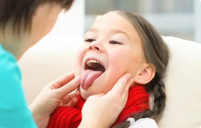 Doctora revisando las amígdalas de la niña