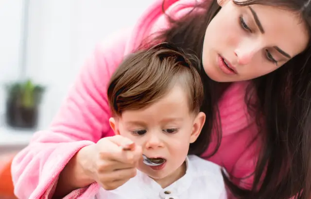 Mamá dando medicamento a bebé