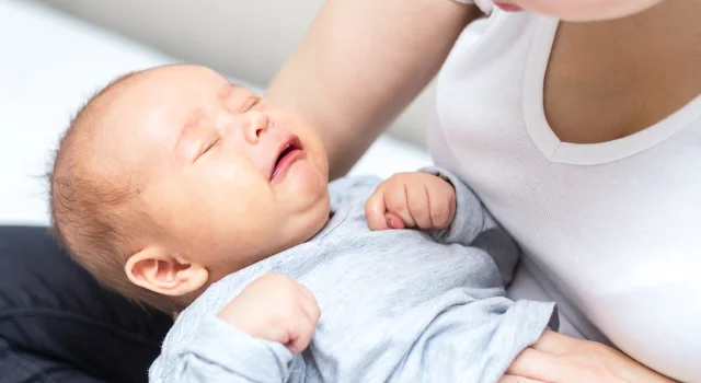 Bebé apretando puños en brazos de su madre